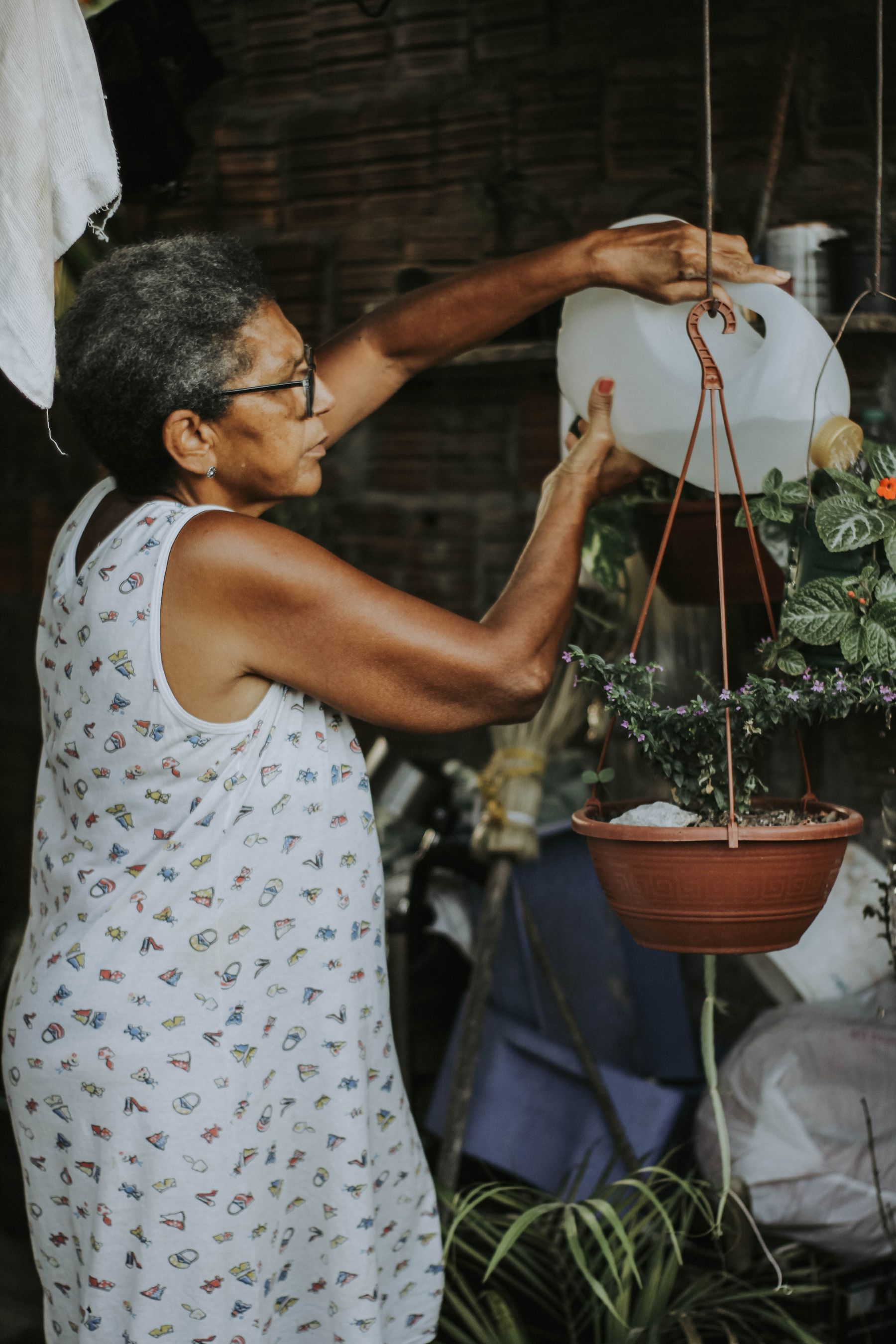 A resident watering the hanging plants by the window
