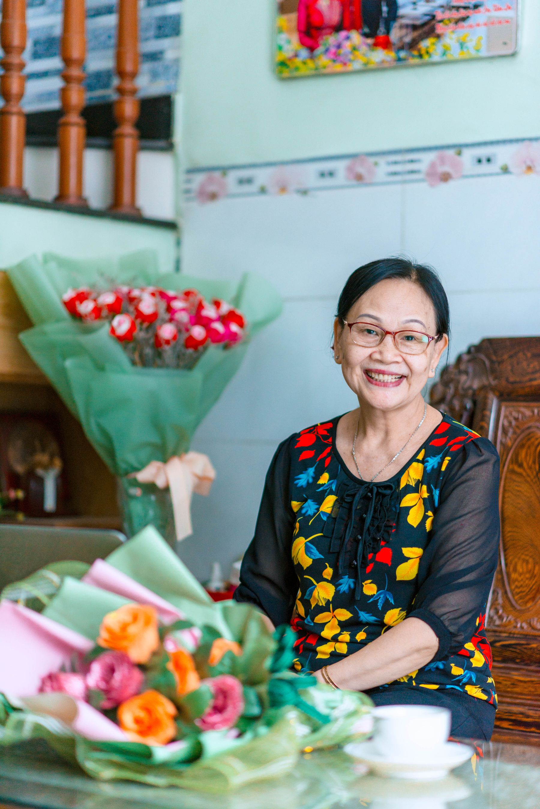 A resident smiling beside the flowers she is arranging