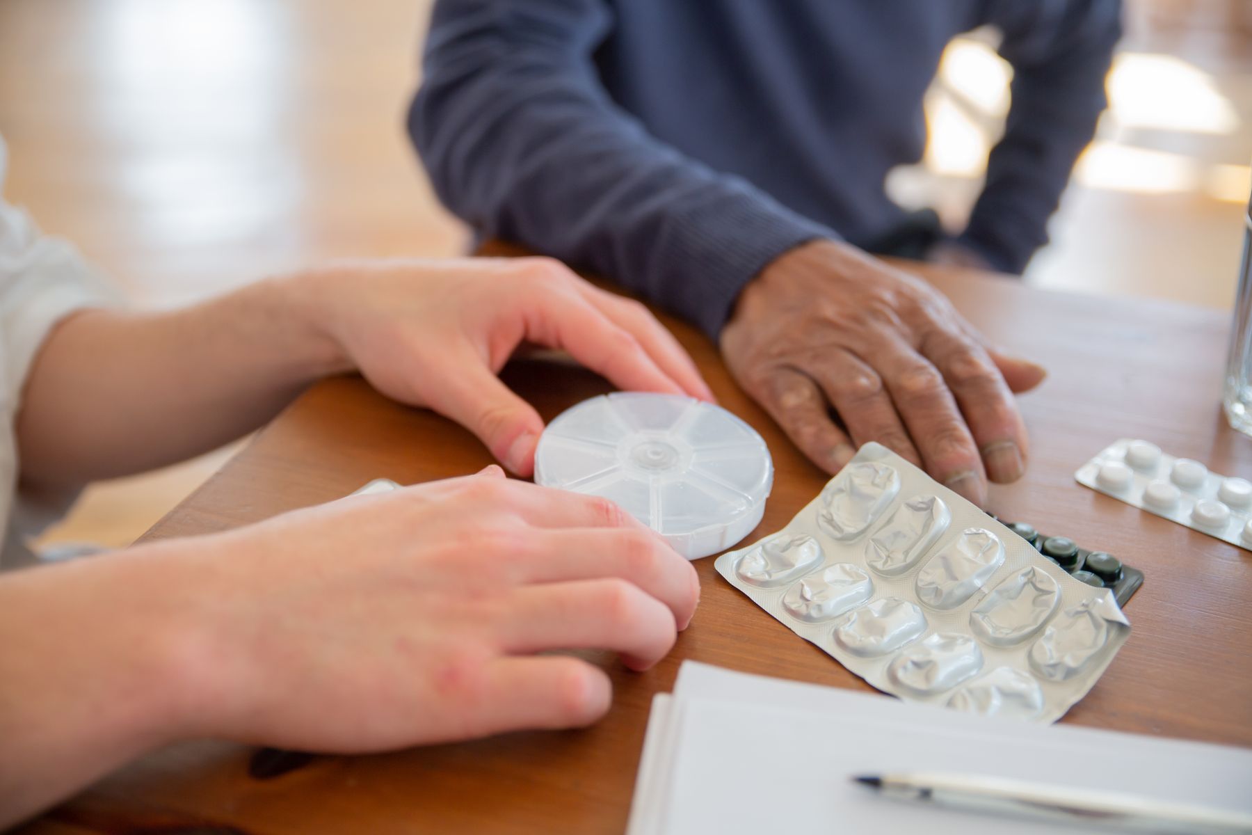 A staff member sorting the week's medications at the table