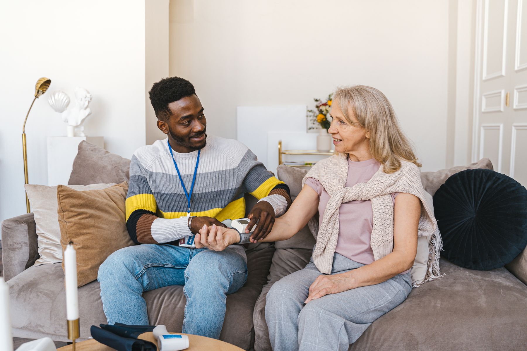 A caregiver sitting with a resident on the couch, checking in on how she is doing